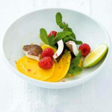 Mango, coconut and raspberry salad with pink peppercorns and mint leaves